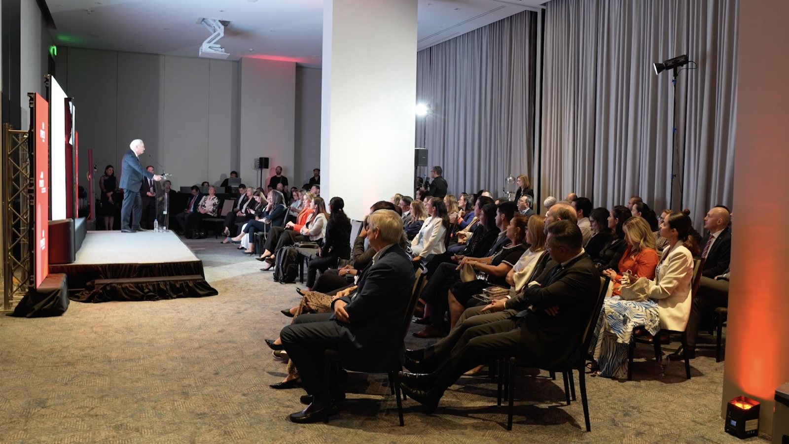 Evento corporativo de BAC con público y orador en tarima